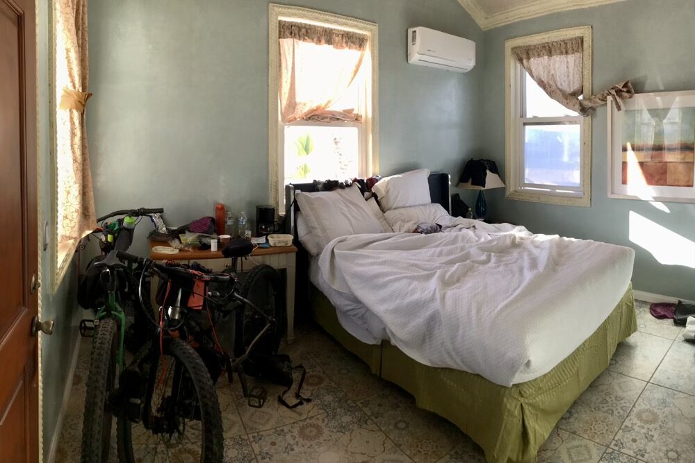 A typical bikers hotel room full of bikes, strewn gear and washing drying on available light shades